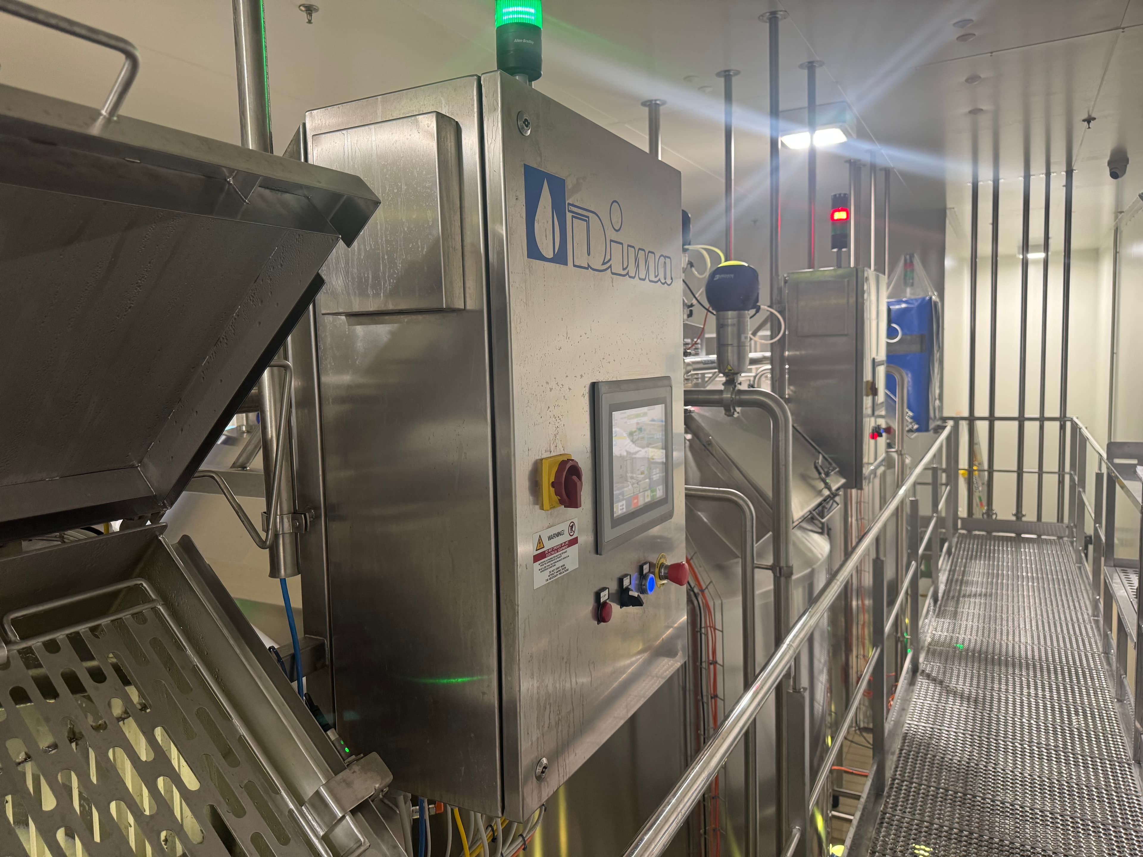 Stainless steel food processing equipment with an operator panel on a production floor